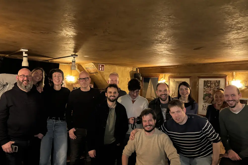 The room at the March Salon, gold walls and lamplight, everyone standing together at the end of the night.