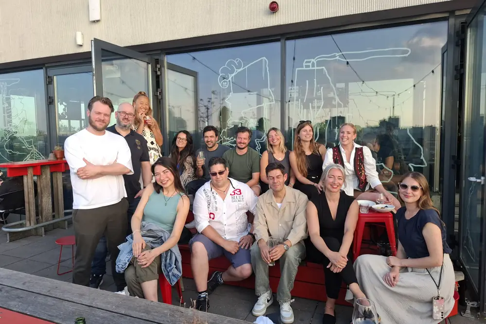 Summer drinks on a rooftop above Amsterdam, the whole group together as the sun goes down.